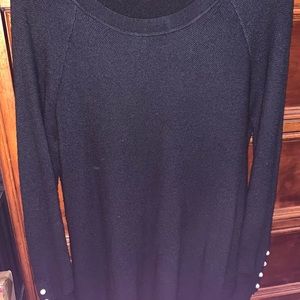 Black tunic sweater with pearl accent buttons on both sleeves.